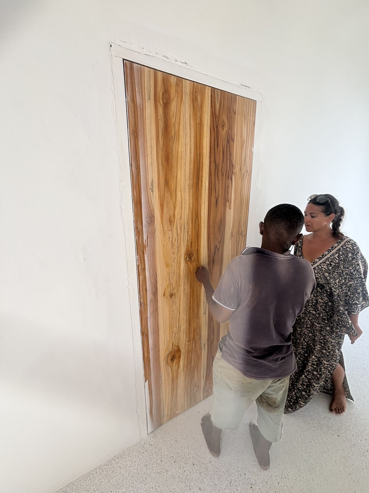 A teak door being fitted into its frame